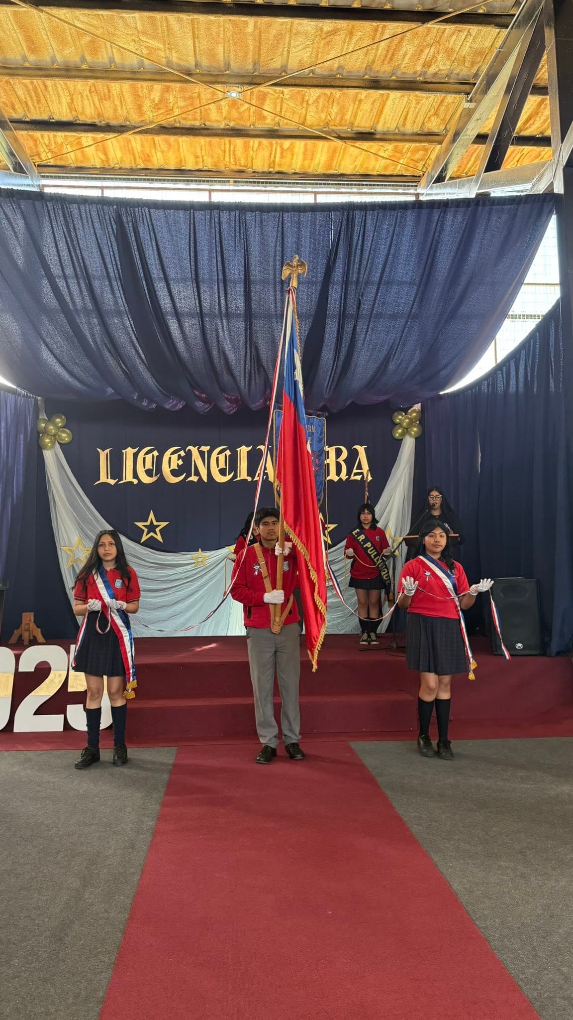 Estudiantes en ceremonia de licenciatura con estandarte institucional