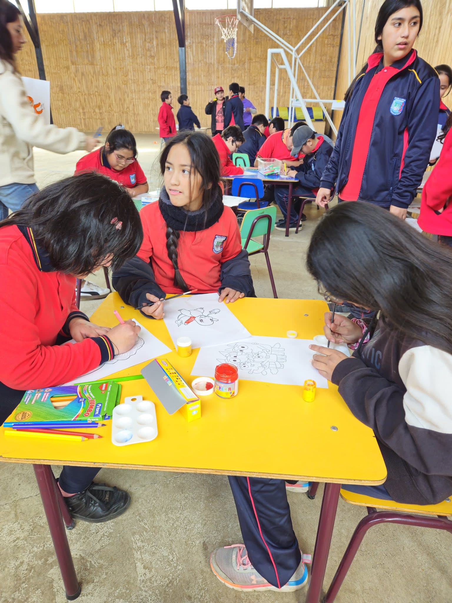 Estudiantes realizando una actividad artística en mesas de trabajo