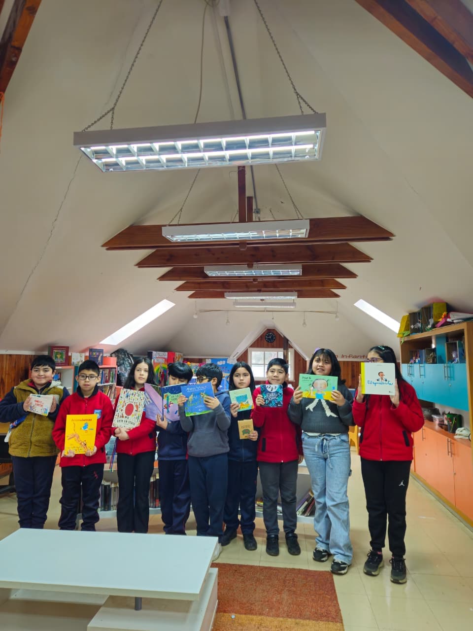 Grupo de estudiantes presentando libros de Amanuta en la biblioteca de la Escuela Rural Pullinque