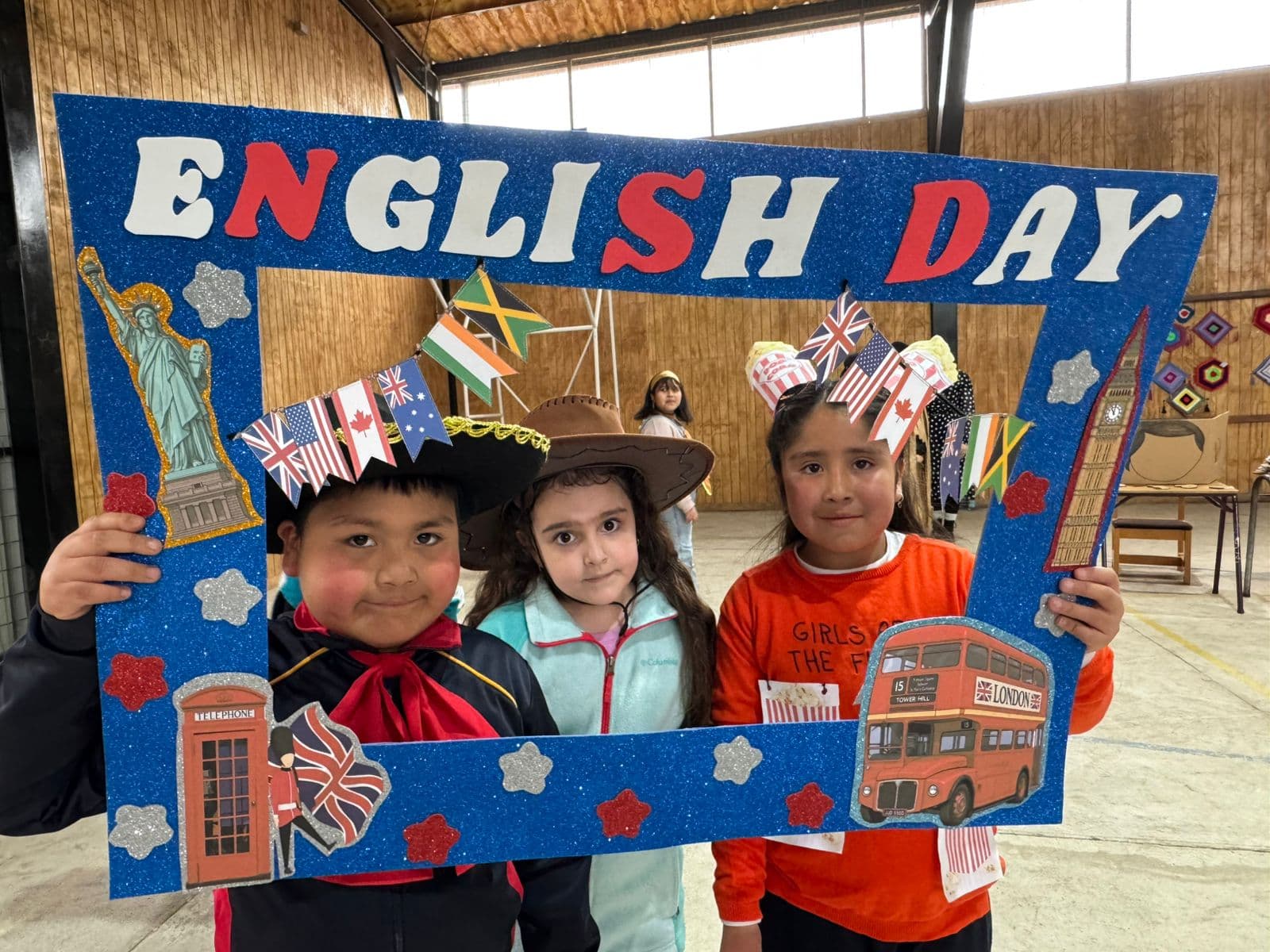 Tres estudiantes con sombreros y accesorios participando en English Day
