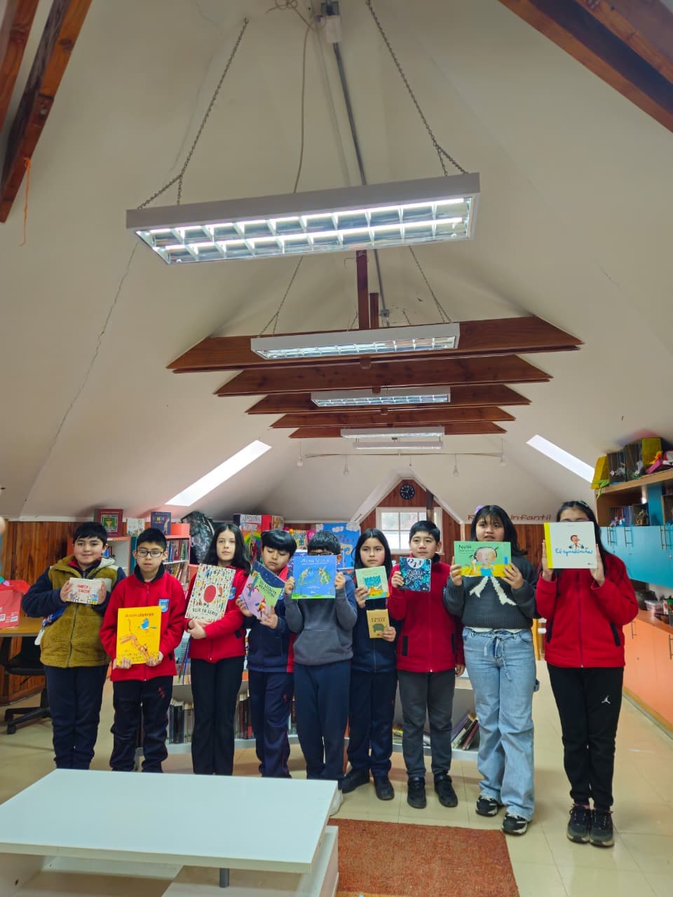 Estudiantes de la Escuela Rural Pullinque mostrando los nuevos libros recibidos en la biblioteca escolar